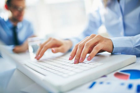 Close-up of young female fingers pushing laptop buttonsの写真素材