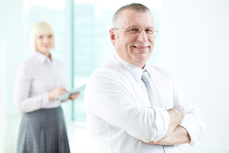 Portrait of smiling boss looking at camera with female standing on backgroundの写真素材