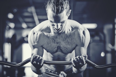 Portrait of sporty topless man lifting weight in gym の写真素材