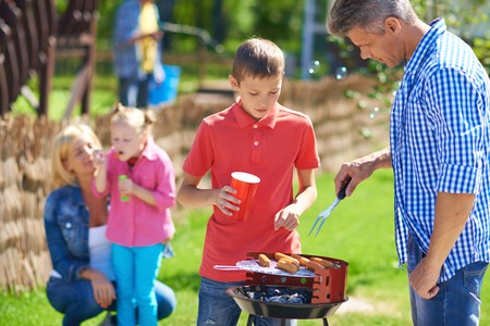Big family frying sausages on grillの写真素材