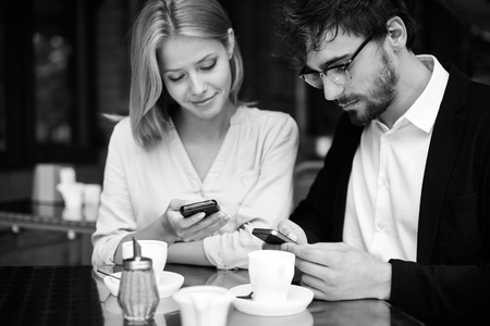 Portrait of young couple using their cellphones in cafeの写真素材