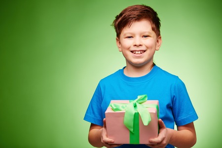 Joyful boy with giftbox looking at camera in isolationの写真素材