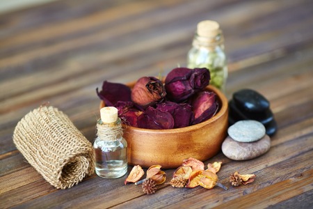 Dry roses, leaves, spa stones and essential oils on wooden surfaceの写真素材
