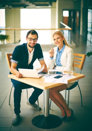 Two white collar workers looking at camera at workplaceの写真素材