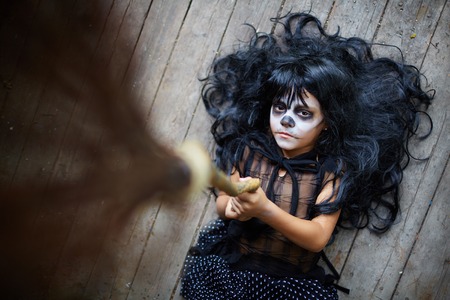 Portrait of eerie girl with broom looking at camera with sulky expressionの写真素材