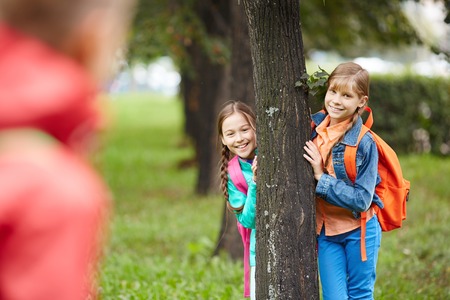 Cute schoolgirls in casual standing by a tree in parkの写真素材