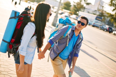 Affectionate travelers with backpacks taking walk in a cityの写真素材