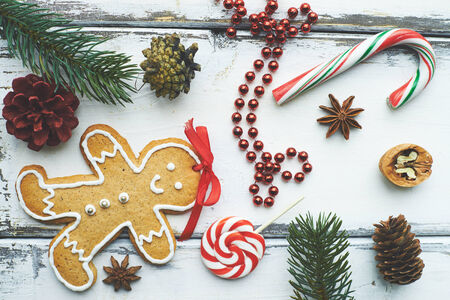 Composition of lollipop, sugar cane, ginger bread, beads, walnut, anise, some cones and conifer on...