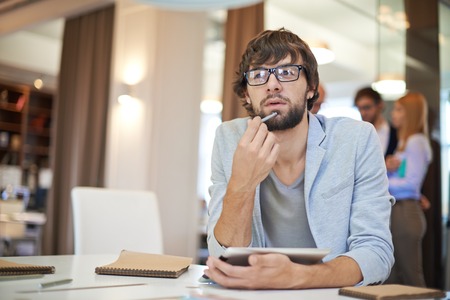 Handsome businessman in casual sitting at workplace on background of his partners
