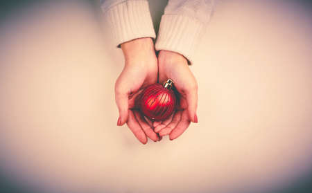 Red decorative toy ball on female hands in isolationの写真素材