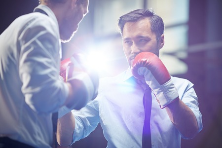 Serious businessman in boxing gloves looking at his rival before attackの写真素材