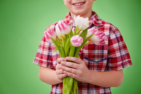 Little boy holding bunch of white and pink tulips