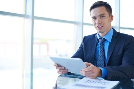 Smiling businessman with touchpad working in office alone