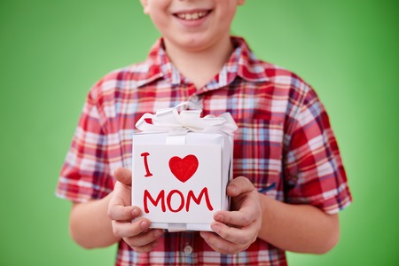 Present for mother in giftbox with note held by a boyの写真素材