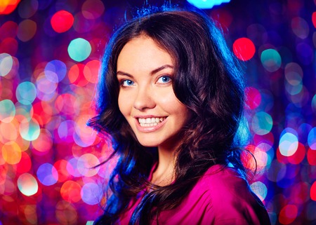 Portrait of beautiful brunette looking at camera with toothy smile over sparkling backgroundの写真素材