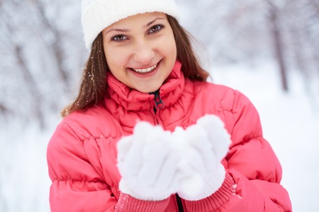 Portrait of pretty girl in winterwear holding snow on palmsの写真素材