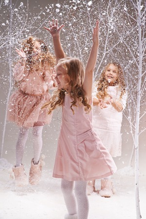 Three little princesses enjoying snow play in amazing winter forestの写真素材