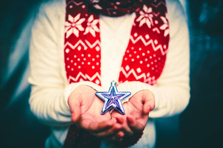 Female hands holding a star-shaped decorationの写真素材