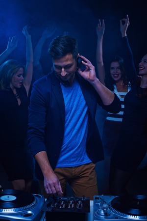 Young stylish deejay at dancing party in night club