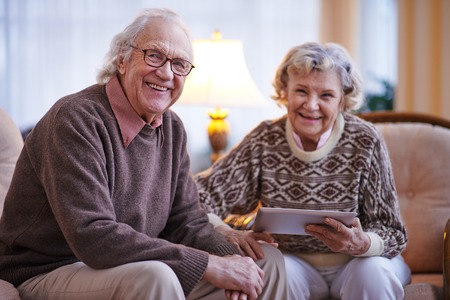 Happy senior couple looking at camera at homeの写真素材