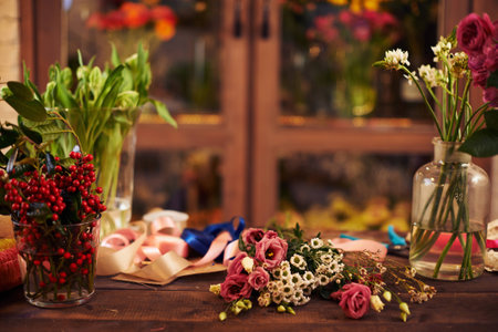 Flowers, berries and decorative ribbons on workplace of florist