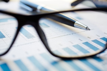 Eyeglasses and pen on business paperの写真素材