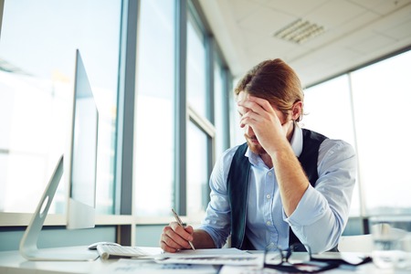 Young fatigue entrepreneur working in officeの写真素材