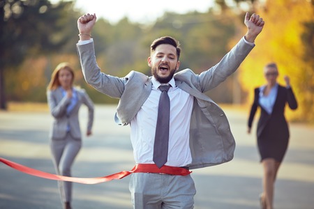 Winning businessman coming to finish with two female colleagues on backgroundの写真素材