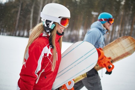 Young female and her boyfriend snowboarding on winter resortの写真素材