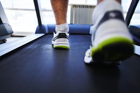 Feet of young man training on special sport equipment in gym