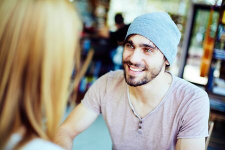 Young guy looking at his girlfriend while listening to herの写真素材