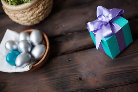 Blue giftbox with violet ribbon and painted Easter eggs near by