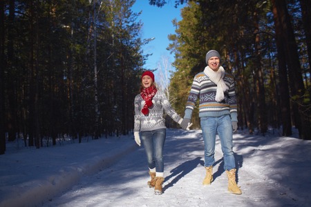 Amorous and ecstatic couple taking walk in winter forestの写真素材