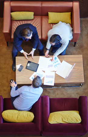 Group of modern businessmen discussing papers at meetingの写真素材