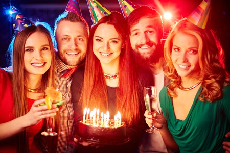 Group of happy friends in birthday caps looking at cameraの写真素材