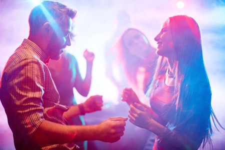 Happy young couple dancing in night clubの写真素材
