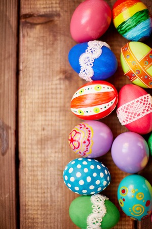 Two rows of painted eggs on wooden backgroundの写真素材