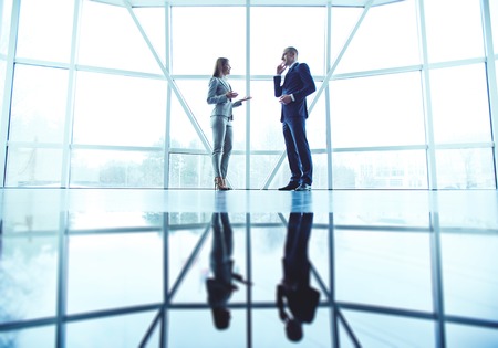 Two confident colleagues interacting in officeの写真素材