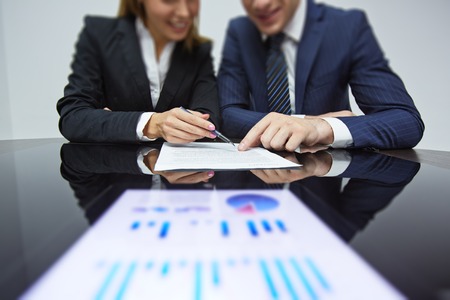 Business partners reading contract at workplace during negotiationの写真素材