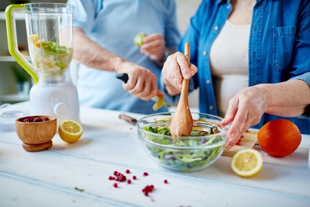 Senior female mixing ingredients of vegetable saladの写真素材