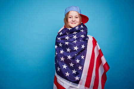 Cute girl wrapping in the American flagの写真素材