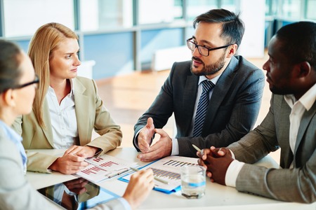 Serious businessman explaining principles of work to his colleagues at meetingの写真素材