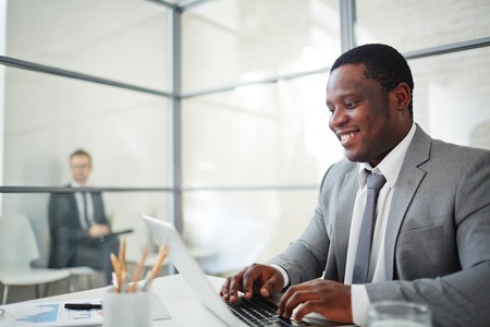 African businessman in formalwear typing on laptopの写真素材