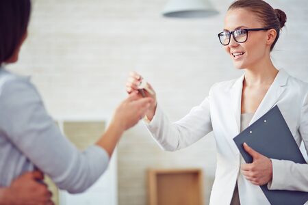 Young female broker giving her client key from new flatの写真素材