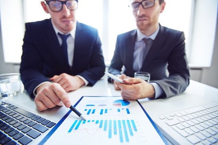Close-up of businessmen analyzing chart at meetingの写真素材