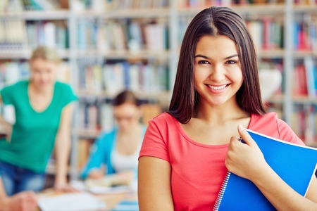 Smiling teenager with copybook looking at cameraの写真素材