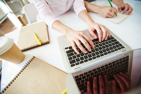 Female student typing on laptop at workplace