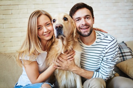 Happy young couple and their pet spending weekend at homeの写真素材