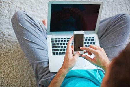 Young man choosing new track from list in cellphoneの写真素材