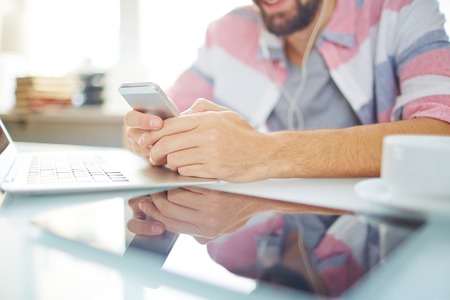 Modern gadgets on workplace and male hands with smartphoneの写真素材